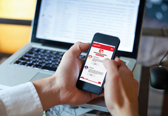 Person holding a mobile phone and in front of a laptop